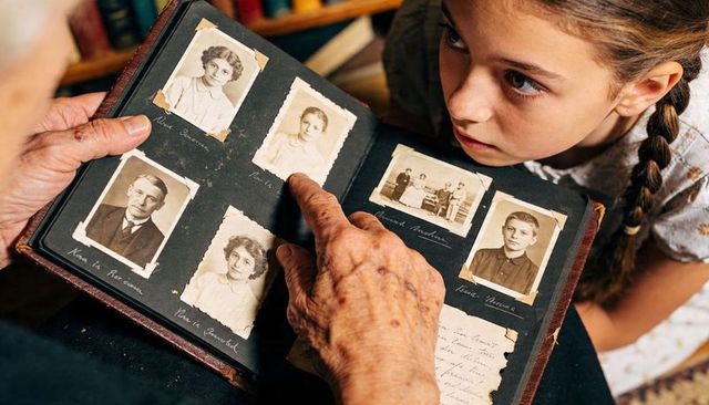 Grandparent and grandchild exploring vintage family album with sepia portraits