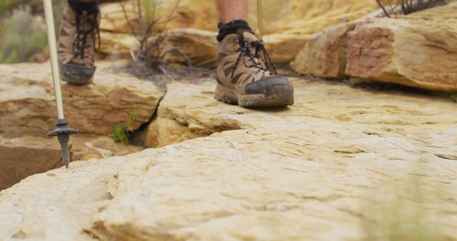 Hiker's boots making contact with a rugged rocky terrain. Usage ideas include marketing for outdoor gear, fitness and wellness campaigns, travel blogs and adventure promotions, hiking trail guides, and destination tourism materials.