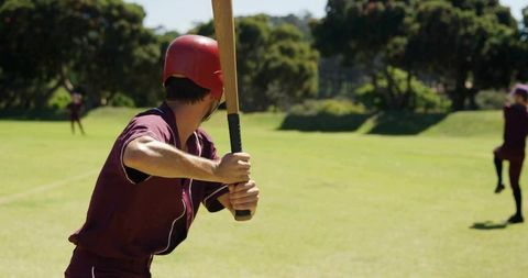 Baseball Player Preparing to Swing Bat in Sunny Park Game