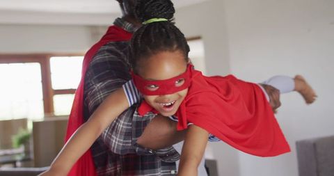 Father and daughter having fun in superhero costumes