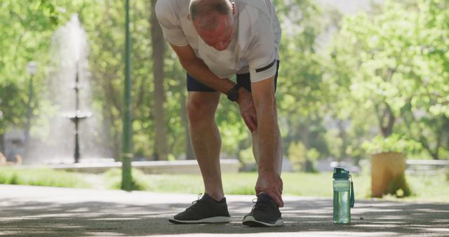 Senior Jogger Stretching in Park with Water Bottle Nearby - Download Free Stock Images Pikwizard.com