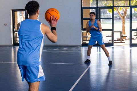 Team Teammates Practicing Basketball in Indoor Gymnasium