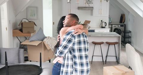 Couple Embracing During Moving Day in Light-Filled Kitchen