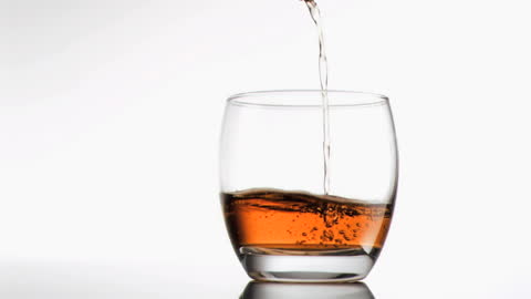 Whiskey Splashing into Glass on White Background