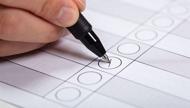 Closeup hand marking bubble on multiple-choice answer sheet with black rollerball pen