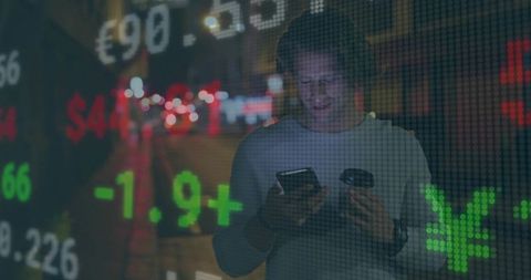 Man Using Smartphone with Real-Time Financial Tickers at Night