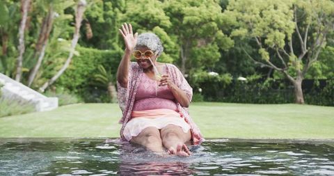 Joyful Senior Woman Relaxing by Pool with Cocktail