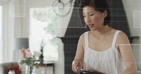 Korean woman using tablet in modern living room with futuristic hud overlay for smart home