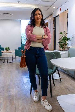 Confident professional woman standing with arms crossed in modern office lounge