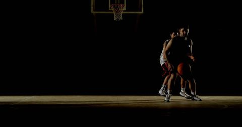 Intense Basketball Game with Young Athletes on Dimly Lit Court