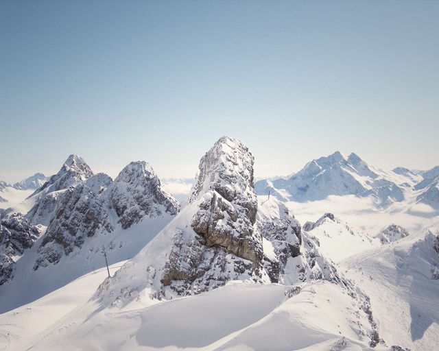 A breathtaking view of rugged, snow-covered mountains under a clear blue sky in winter. Ideal for use in travel and adventure magazines, outdoor adventure advertisements, landscape photography showcases, or as inspirational backgrounds. Conveys a sense of tranquility, nature’s raw beauty, and adventurism.