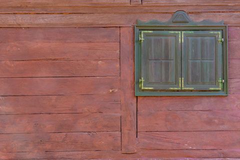 Rustic Red Wooden Planks Showing Small Green Double Shutter Window with Brass Hinges