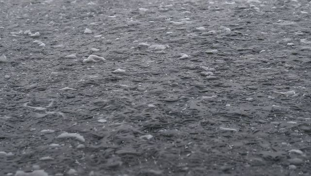 Rain falling on dark ocean surface creating ripples and foam texture for moody backgrounds