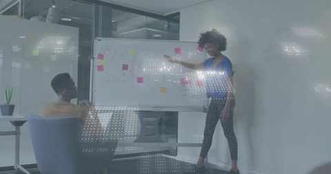 Young woman presenting strategy on whiteboard during collaborative brainstorming session