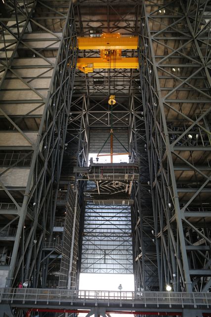 Heavy-lift crane is lifting the C-level work platform for installation in High Bay 3 of the Vehicle Assembly Building at NASA's Kennedy Space Center. The advanced engineering and ground system operations are featured prominently, showcasing NASA's preparations for the Space Launch System (SLS) rocket and the Orion spacecraft. This imagery is useful for showcasing engineering marvels, construction technology, space missions, and the continuation of NASA’s journey to Mars.