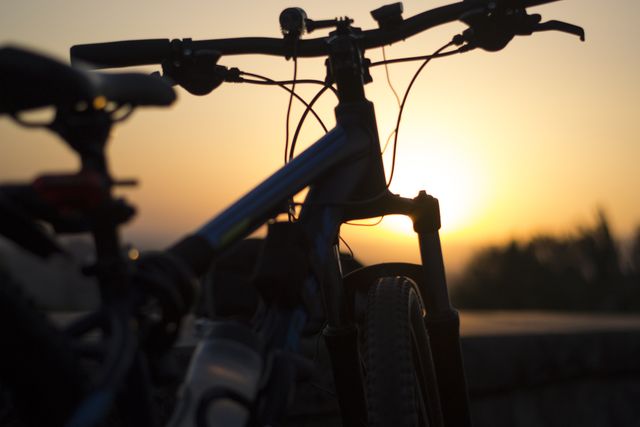 Depicting a mountain bike silhouetted against a vibrant sunset, this image can be used to evoke a sense of adventure, tranquility, and the love for outdoor activities. It is ideal for recreations, sports, travel promotions, or inspirational content that encourages a healthy lifestyle and enjoying nature.