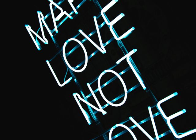 Bright neon sign displaying the words 'Make Love Not War' in blue light. Can be used for articles or designs focusing on peace, love, inspiration, motivational messages, or modern design trends.