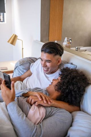 Cheerful Couple Laughing Together in Cozy Bedroom Setting