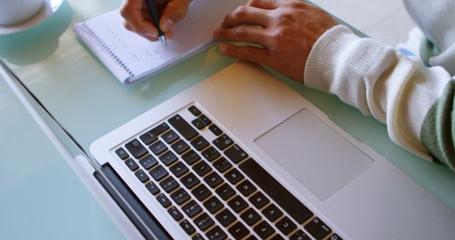 Person Taking Notes on Notepad Beside Laptop on Glass Desk - Download Free Stock Images Pikwizard.com