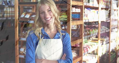 Smiling retail worker wearing apron and denim shirt standing in warm artisanal market interior
