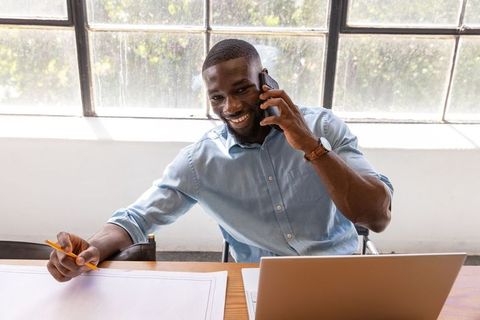 Professional Designer Sketching and Collaborating on Smartphone in Modern Studio