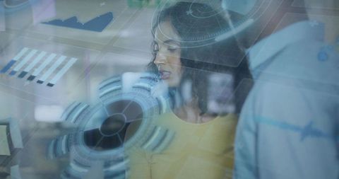 Woman and Coworker Analyzing Holographic Data on Glass Display in Modern Office