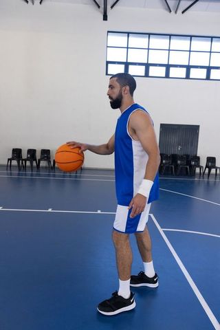 Focused Athlete Dribbling Basketball on Indoor Court