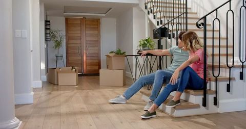 Happy Young Couple Relaxing in New Home Surrounded by Moving Boxes