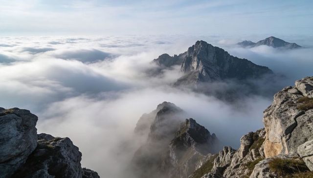 Rising granite peak emerging through sea of clouds on rugged alpine ridge