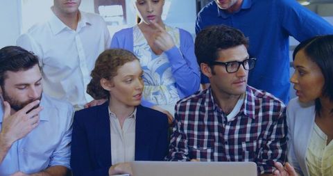 Diverse Team Brainstorming Around Laptop in Open-Plan Office