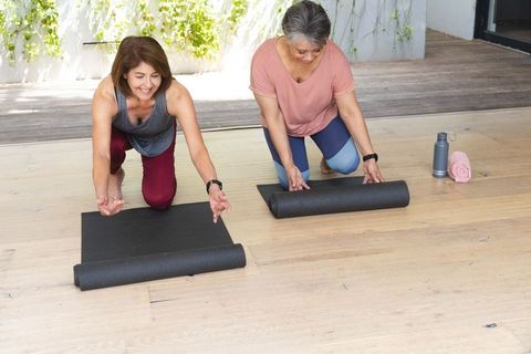 Senior and Hispanic Women Preparing for Outdoor Yoga Session