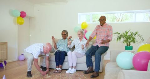 Happy Senior Friends Celebrating with Balloons and Laughter Indoors