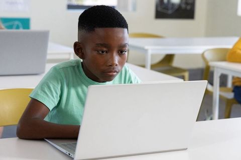 African american boy using laptop in classroom studying and focusing on digital learning