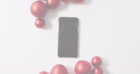 Smartphone with red ornaments on white holiday-themed background