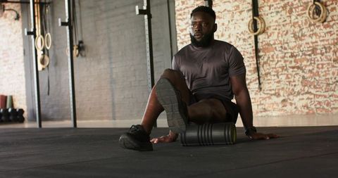 Man in gym using foam roller for muscle recovery