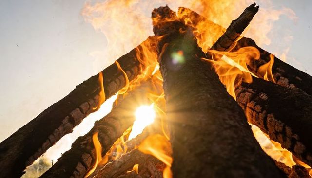 Burning logs towering over sunflare dramatic bonfire close-up with flames and embers