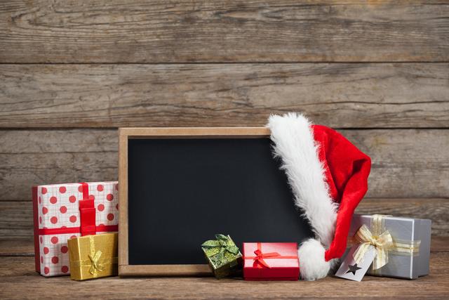 Slate, gift box and santa hat arranged on wooden table during chirtsmas time