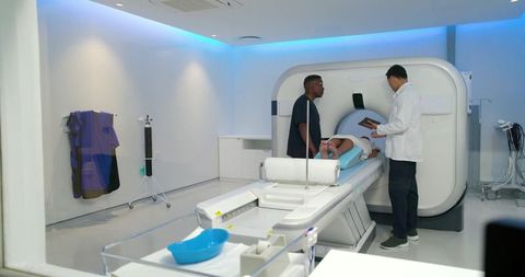 Medical team preparing african american patient for ct scan while technician consulting tablet
