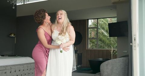 Bride and Bridesmaid Sharing Joyful Embrace on Wedding Morning
