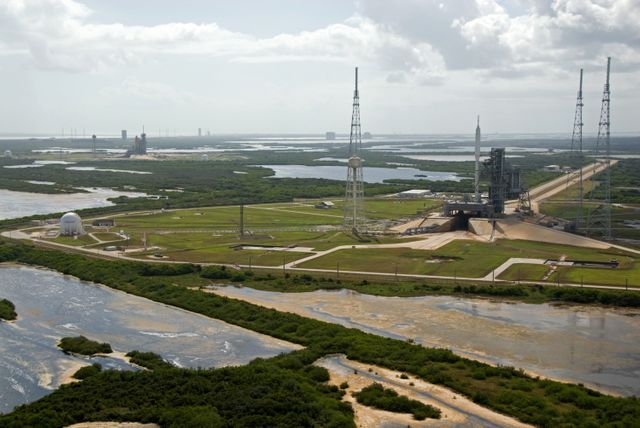 CAPE CANAVERAL, Fla. – At NASA's Kennedy Space Center in Florida, the 327-foot-tall Ares I-X rocket awaits liftoff on Launch Pad 39B on its upcoming flight test.  In the distance are space shuttle Atlantis on Kennedy's Launch Pad 39A, and the pads and processing facilities on Cape Canaveral Air Force Station.  This is the first time since the Apollo Program's Saturn rockets were retired that a vehicle other than the space shuttle has occupied the pad.  Modifications to the pad to support the Ares I-X included the removal of shuttle unique subsystems, such as the orbiter access arm and a section of the gaseous oxygen vent arm, and the installation of three 600-foot lightning towers, access platforms, environmental control systems and a vehicle stabilization system.  Part of the Constellation Program, the Ares I-X is the test vehicle for the Ares I.  The Ares I-X flight test is set for Oct. 27.  For information on the Ares I-X vehicle and flight test, visit http://www.nasa.gov/aresIX.    Photo credit: NASA/Kim Shiflett