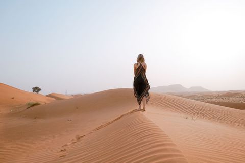Woman Strolling on Golden Sand Dunes at Sunrise