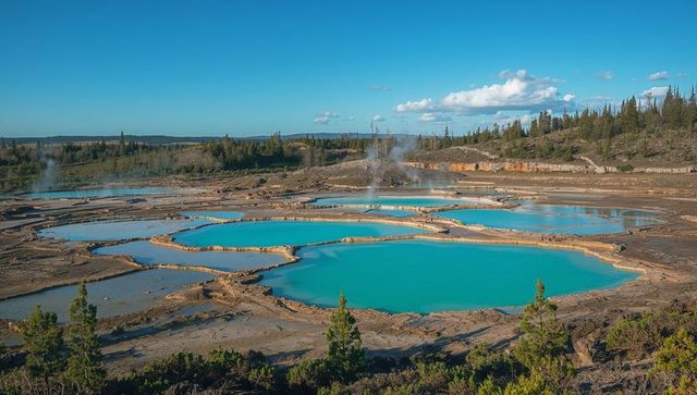 Turquoise geothermal terraced pools on overlook with travertine basins and steam