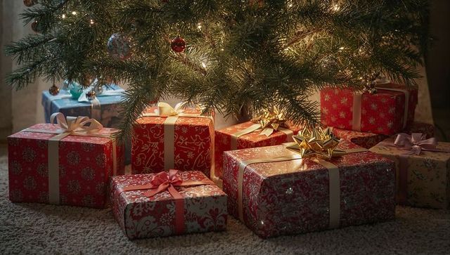 Glowing wrapped gifts resting beneath lit evergreen tree with gold star bow