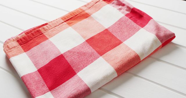Close up of folded red and white checkered blanket on white background with copy space. Picnic day, food and nature concept.