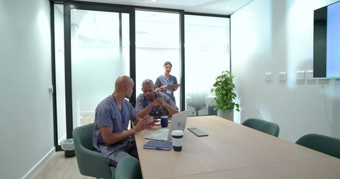 African medical team discussing patient care in modern meeting room with laptop and tablet
