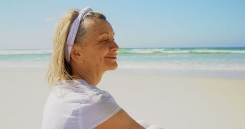 Senior Woman Meditating on Sunlit Beach - Download Free Stock Images Pikwizard.com