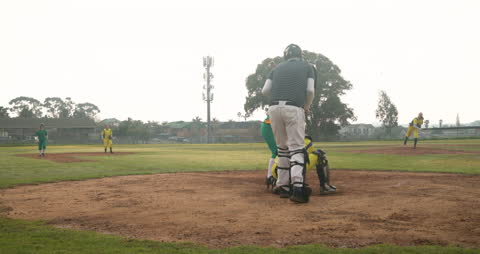 Youth Baseball Game with Pitcher Throwing to Catcher on Sunny Field