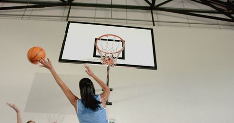 Female basketball players attempting score in indoor gym