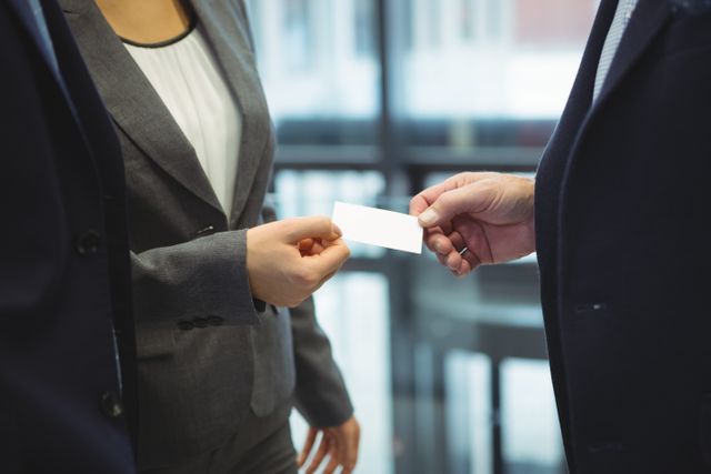 Business executives exchanging business cards in an office setting. Ideal for illustrating networking, professional meetings, corporate introductions, and business partnerships. Useful for business-related articles, corporate websites, and professional networking content.