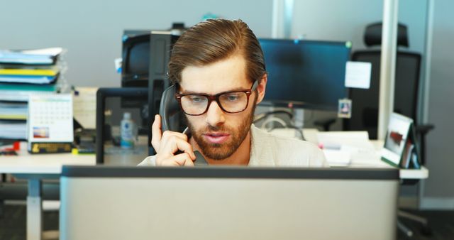 Focused Young Professional Man Talking on Phone at Office Desk - Download Free Stock Images Pikwizard.com